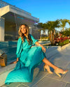 Side View of Model Seated by Pool Wearing Teal Maxi Dress with Tiered skirt and 3/4 Sleeves