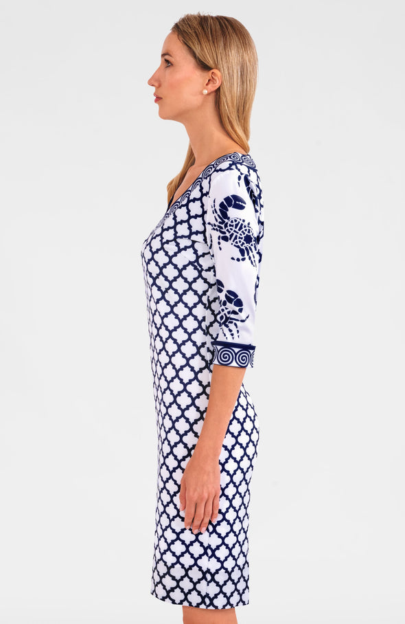 Blonde woman facing sideways wearing navy and white geometric print 3/4 sleeve dress with contrast crab print on sleeves 