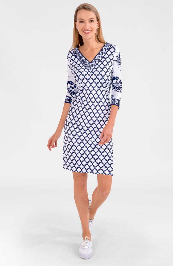Blonde woman wearing navy and white geometric print 3/4 sleeve dress with contrast crab print on sleeves and white tennis shoes 