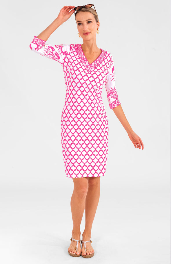 Blonde woman wearing pink and white geometric print 3/4 sleeve v-neck dress with contrast crab print on sleeves with white and gold strappy sandals with sunglasses on her head