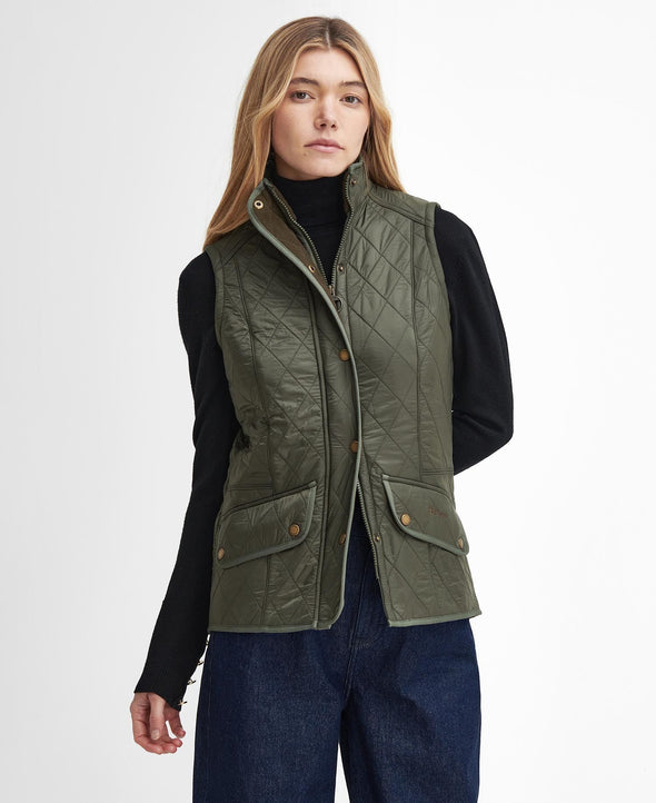 Women in jeans and black turtle neck with dark green Barbour vest on top