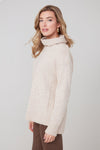 Woman wearing a cream-colored sweater against a plain background