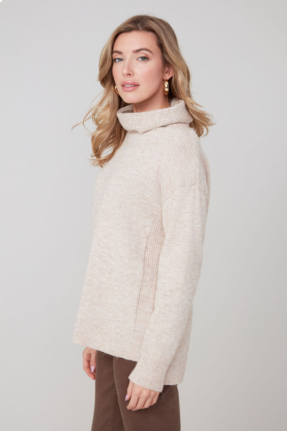 Woman wearing a cream-colored sweater against a plain background
