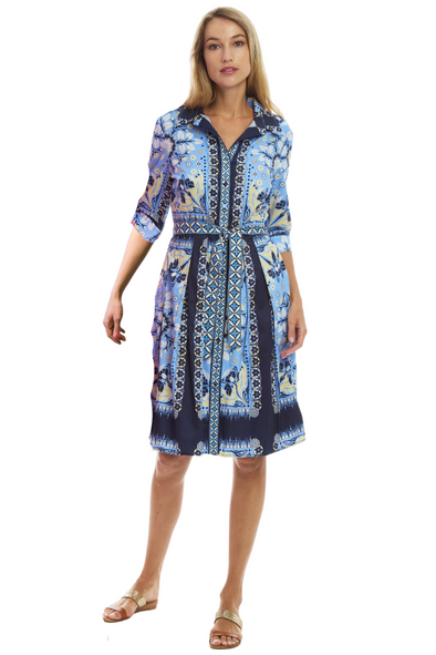 Model in a knee length, tie waist dress with a belted waist. It has a navy, light blue, and yellow pattern. 