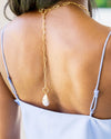 Model wearing necklace down her back 