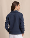 Woman wearing a navy blue textured jacket against a beige background