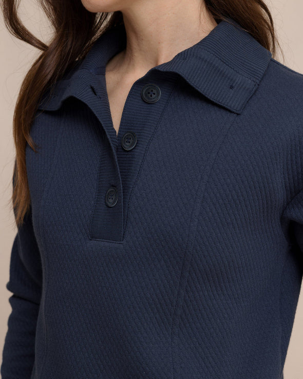 Navy blue textured sweater with collar and buttons on a beige background