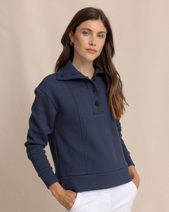 Woman wearing a navy blue textured sweater against a beige background