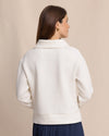 Woman wearing a white jacket against a beige background