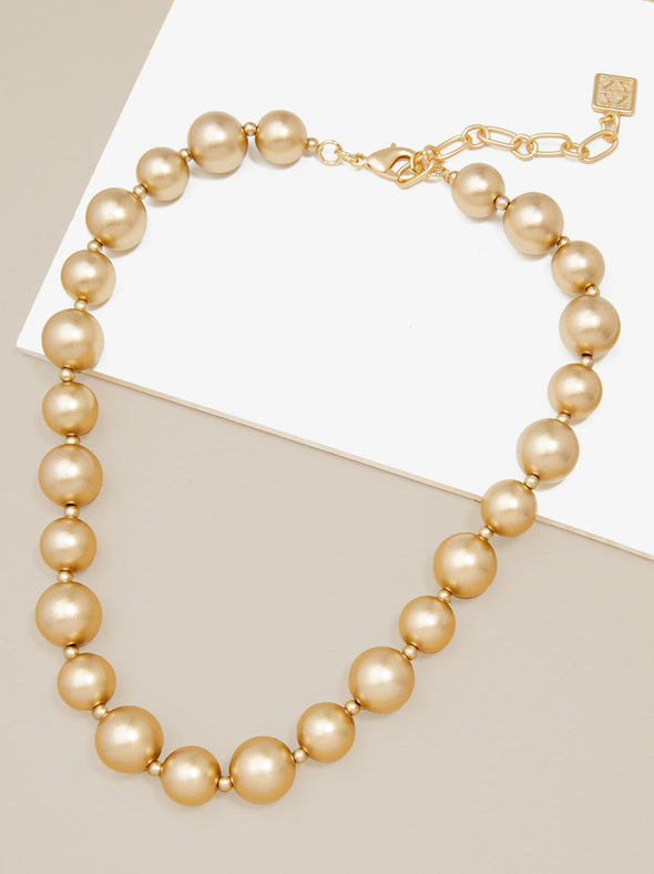 Zenzii Chunky Matte Gold Beaded Necklace layed flat on two-tone display