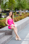 Model sitting outside wearing Jude Connally Bailey Dress in Spring Pink