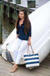 Model leaning against a boat in Renuar Ankle Pants White