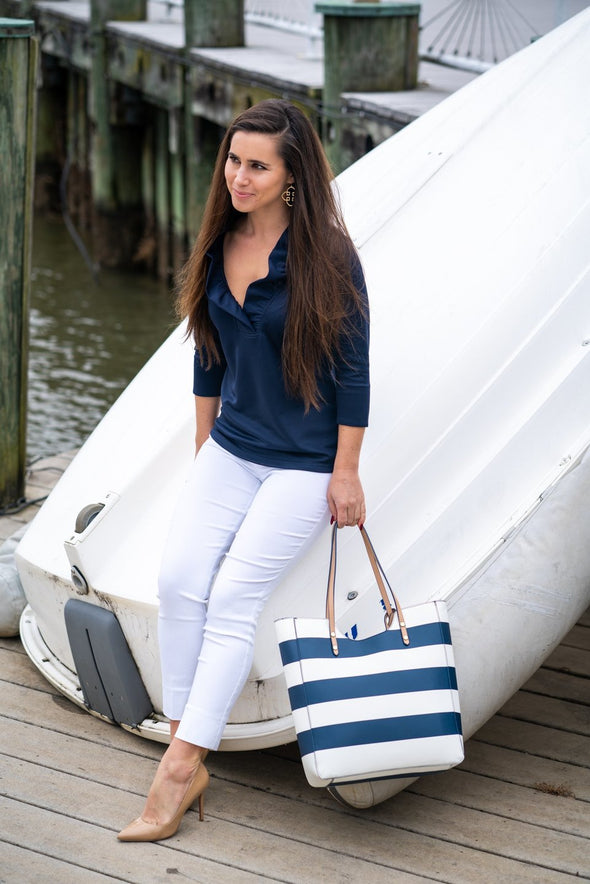 Model leaning against a boat in Renuar Ankle Pants White