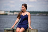 Close up of model sitting on a pier wearing Jude Connally Bailey Dress in Navy