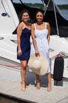 Two models on a dock, left model wearing Jude Connally Bailey Dress in Navy