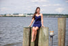 Model seated on pier wearing Two models on a dock, right model wearing Jude Connally Bailey Dress in Navy