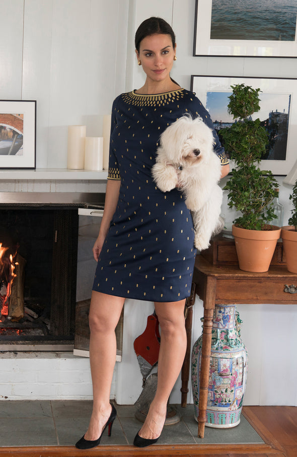 Model wearing Gretchen Scott Rocket Girl Dress in Navy/Gold holding dog